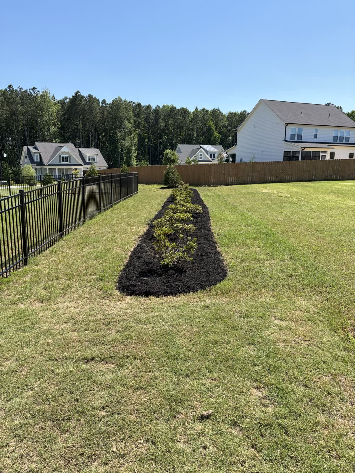 Long residential planting bed finished with fresh mulch
